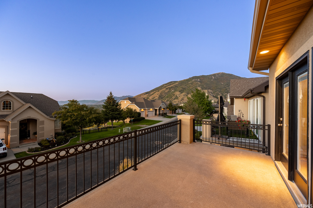Patio terrace at dusk featuring balcony and a mountain view