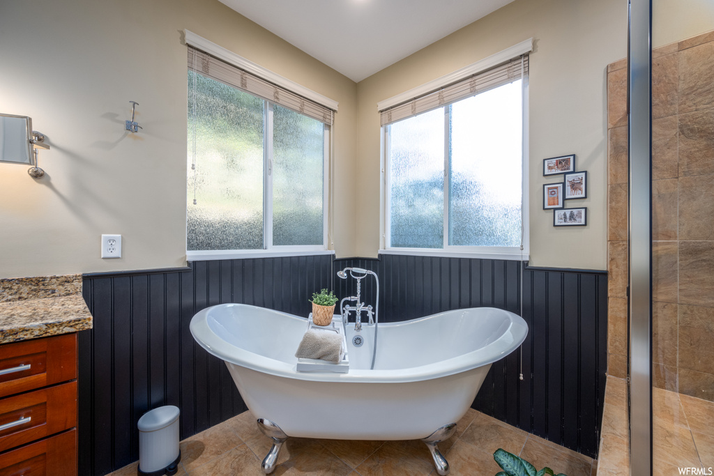 Bathroom featuring vanity, tile flooring, and a washtub