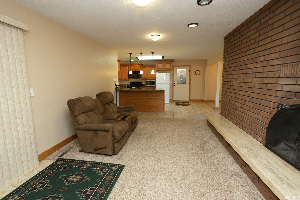 Living room with brick wall, light colored carpet, and a textured ceiling
