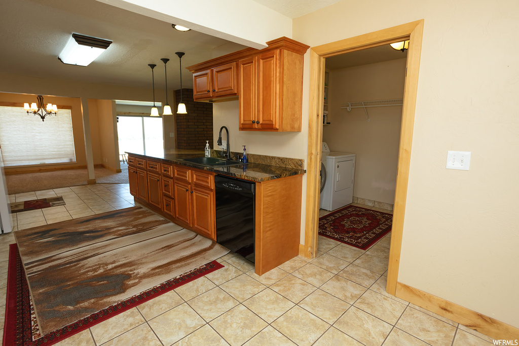 Kitchen with an inviting chandelier, washer and clothes dryer, black dishwasher, decorative light fixtures, and washbasin