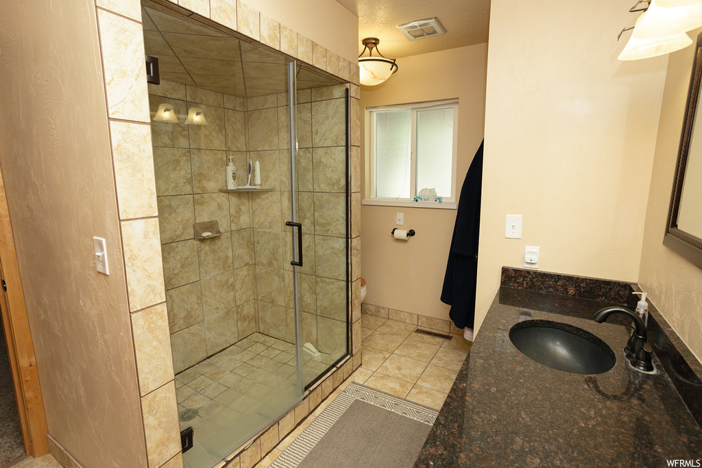 Bathroom featuring tile floors, toilet, an enclosed shower, and washbasin