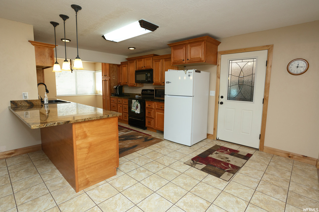 Kitchen featuring stone countertops dark, sink, electric stove, decorative light fixtures, and white refrigerator