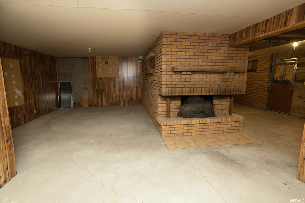 Basement with brick wall, wood walls, and a brick fireplace