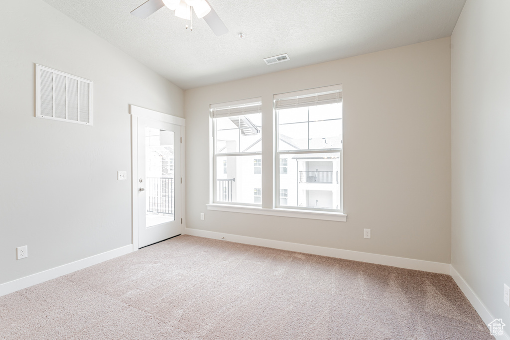 Empty room with a healthy amount of sunlight, carpet floors, and ceiling fan