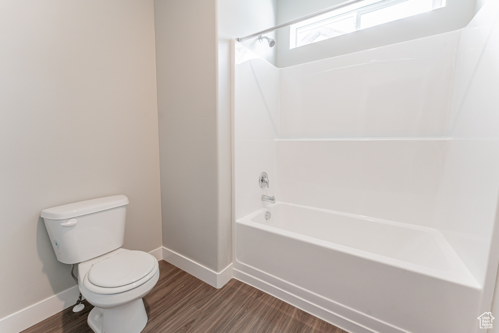 Bathroom featuring tub / shower combination, hardwood / wood-style flooring, and toilet