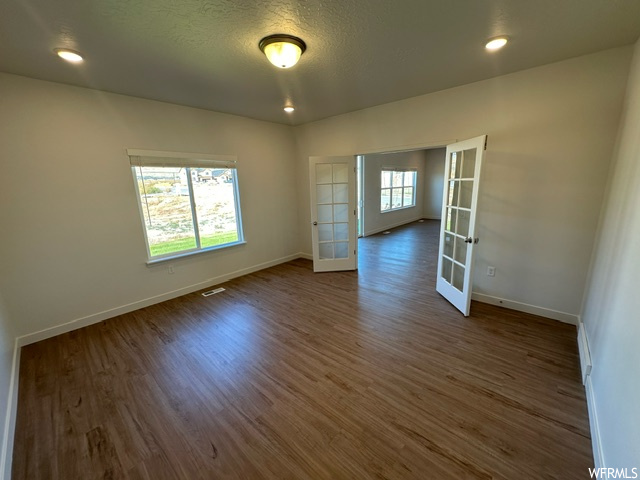 Hardwood floored empty room featuring a textured ceiling and french doors