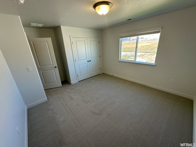 Bedroom with a textured ceiling and light carpet