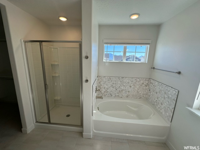 Bathroom featuring independent shower and bath and light tile floors