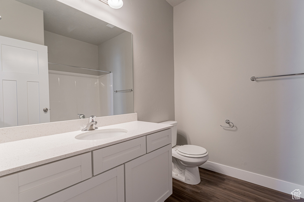 Bathroom featuring hardwood / wood-style floors, vanity with extensive cabinet space, and toilet