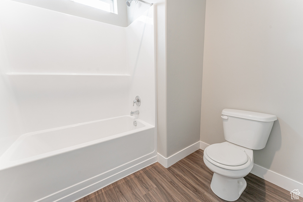 Bathroom featuring wood-type flooring, shower / bathtub combination, and toilet