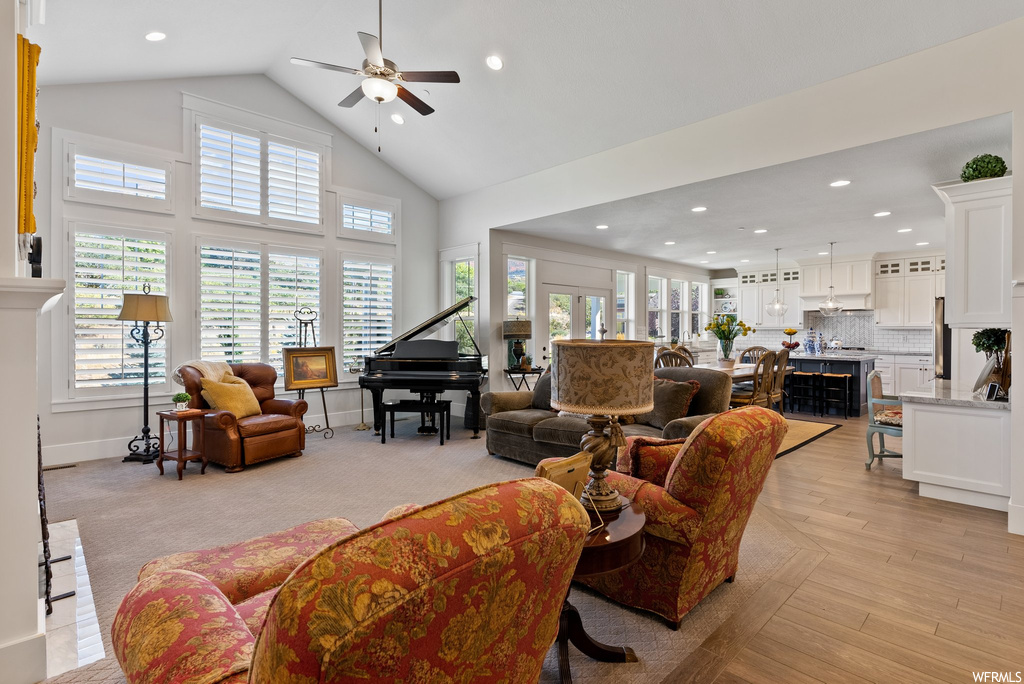 Hardwood floored living room featuring vaulted ceiling, a high ceiling, and ceiling fan