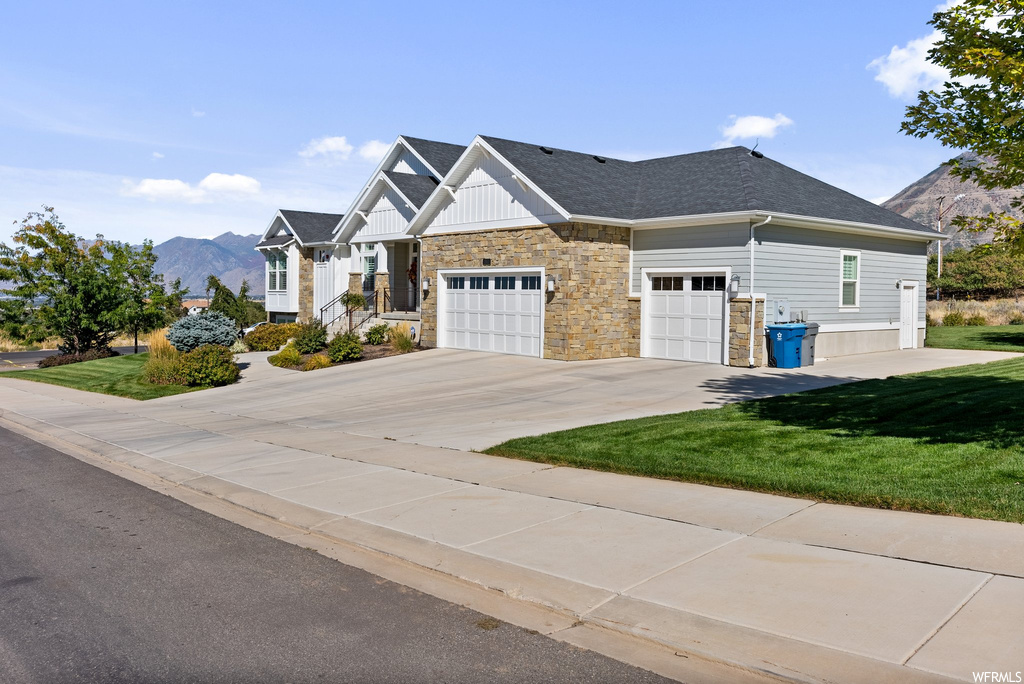 View of front of house featuring a mountain view, garage, and a front lawn
