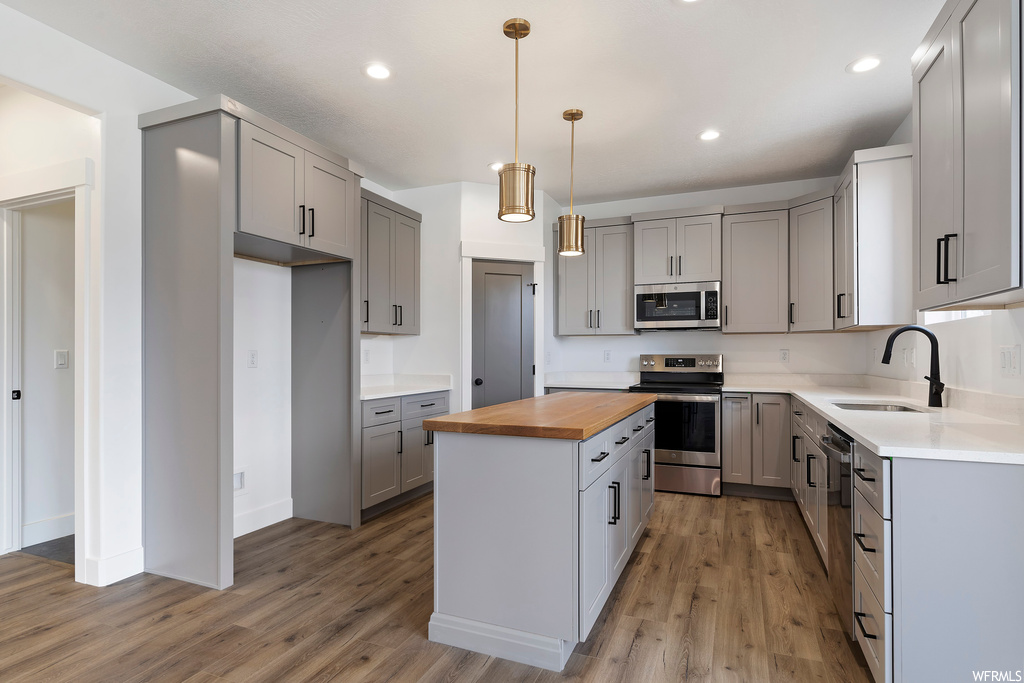 Kitchen with a center island, sink, light hardwood / wood-style flooring, stainless steel appliances, and butcher block counters