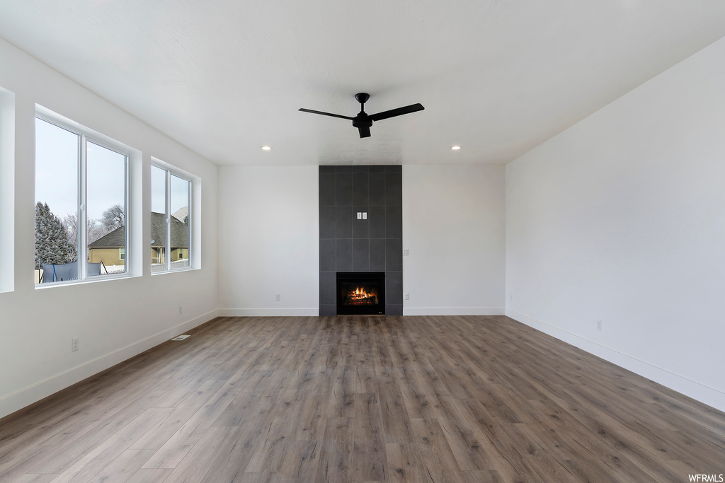 Unfurnished living room with light wood-type flooring, tile walls, and a tiled fireplace