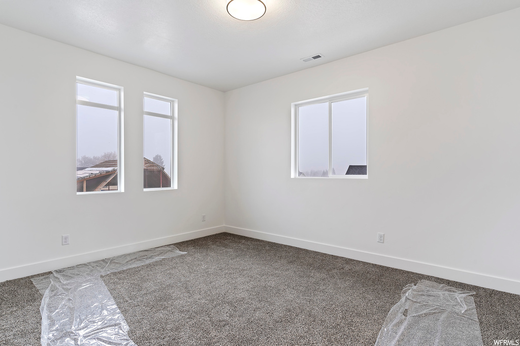 Empty room with dark carpet and plenty of natural light