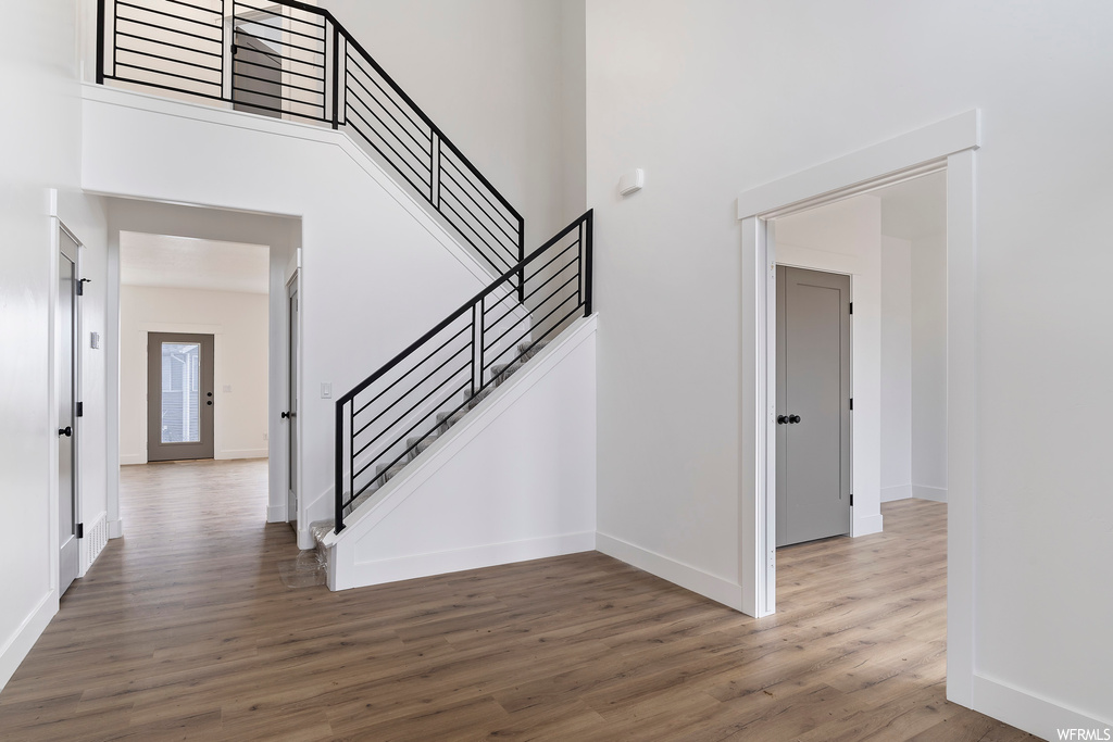 Stairs with a high ceiling and hardwood / wood-style flooring