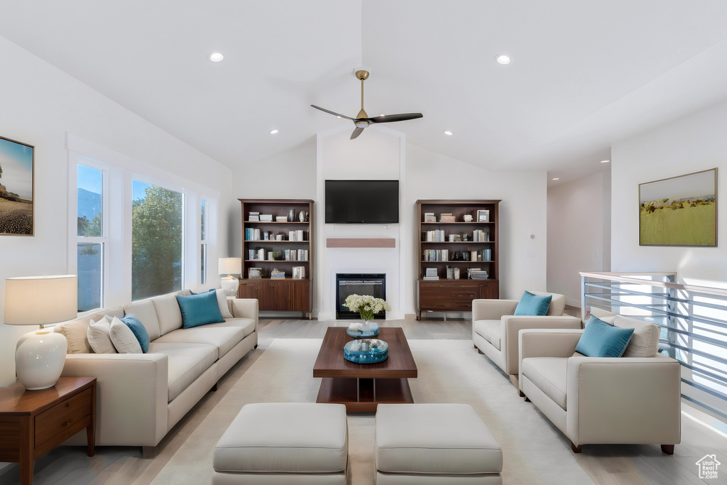 Living room with light wood-type flooring, high vaulted ceiling, and ceiling fan