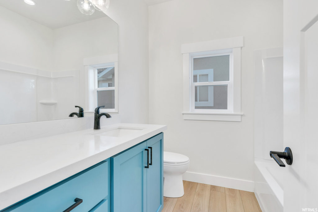 Full bathroom featuring vanity with extensive cabinet space, shower / washtub combination, mirror, and light hardwood floors