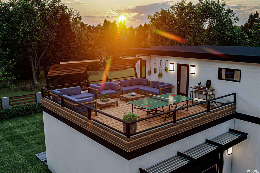 Deck at dusk featuring a lawn and an outdoor living space