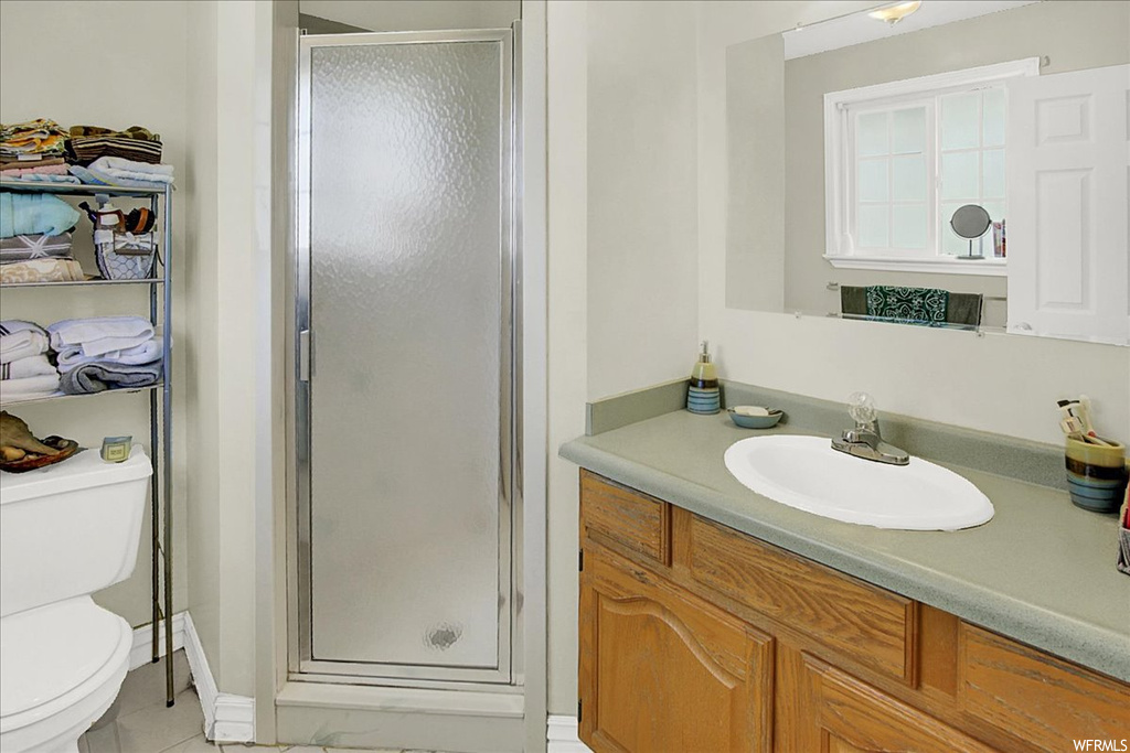 Bathroom with vanity, light tile flooring, mirror, and a shower with shower door