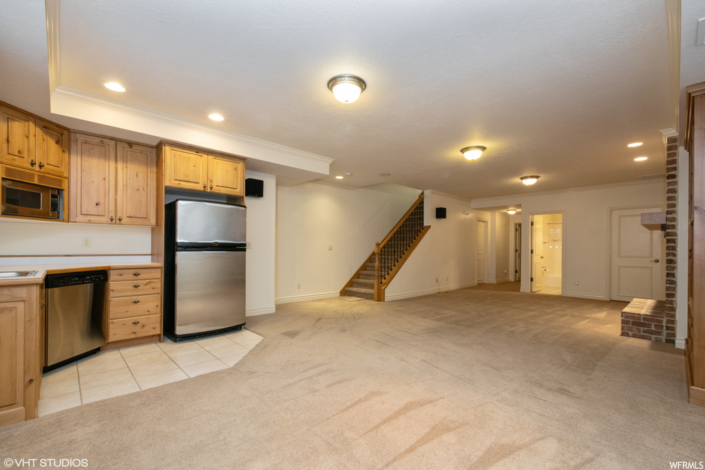 Kitchen with countertops light, ornamental molding, light colored carpet, and appliances with stainless steel finishes
