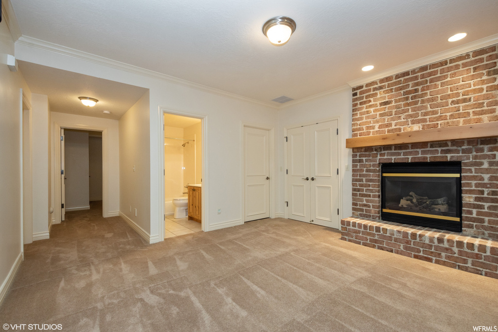 Unfurnished living room with light colored carpet, a brick fireplace, and ornamental molding