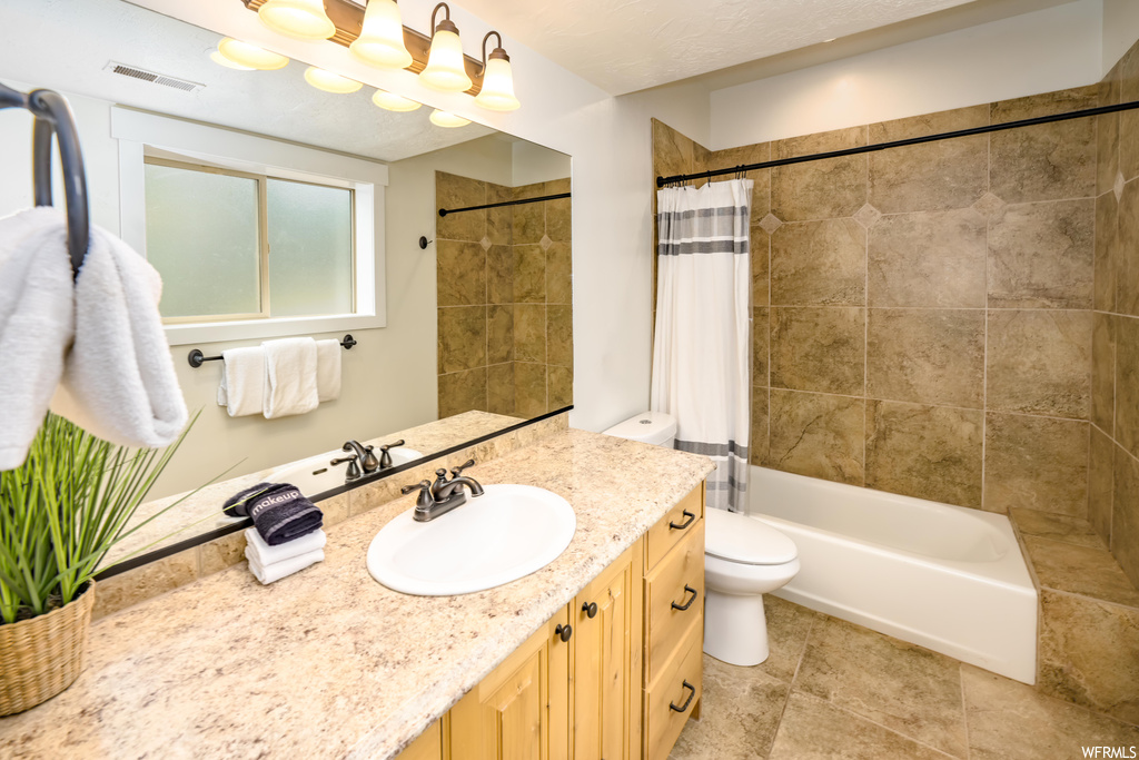 Full bathroom featuring vanity, shower / bath combo, mirror, and light tile floors