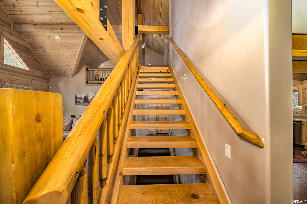 Staircase featuring wood ceiling, vaulted ceiling, and hardwood flooring