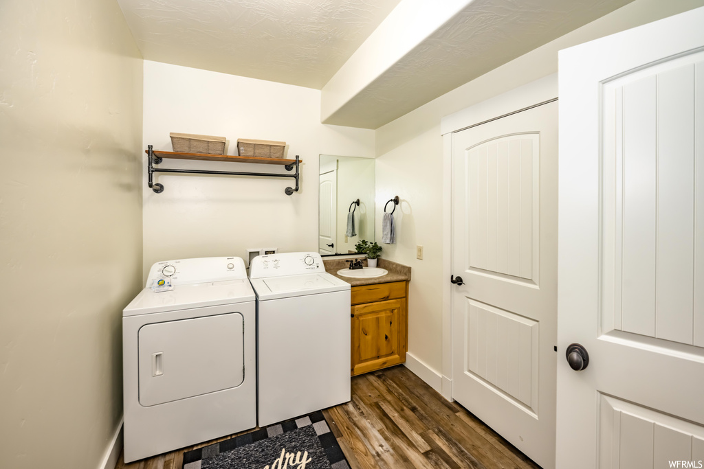 Clothes washing area featuring hardwood flooring and washing machine and clothes dryer