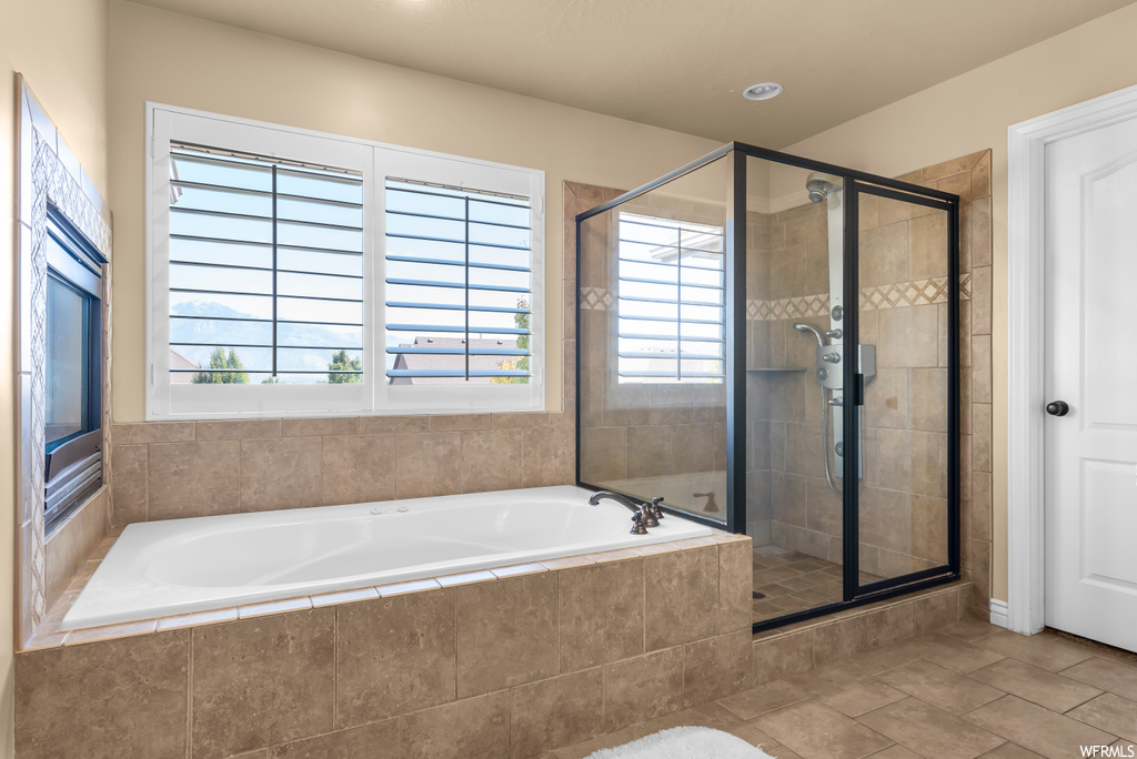 Bathroom featuring shower with separate bathtub and light tile floors