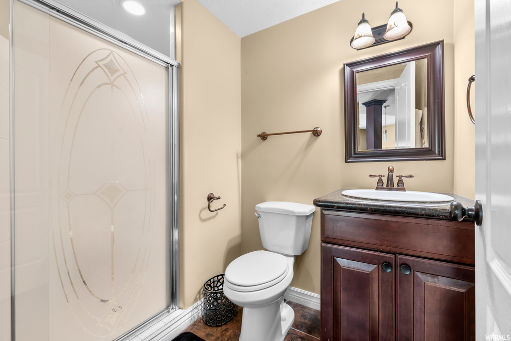 Bathroom featuring tile flooring, vanity with extensive cabinet space, mirror, and a shower with door