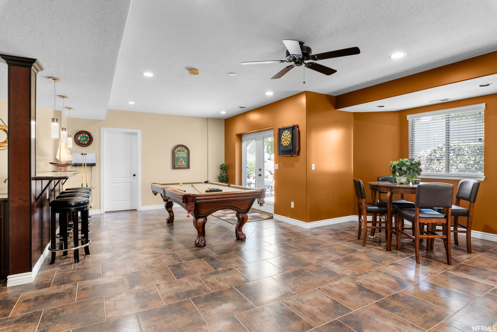 Playroom featuring ceiling fan, dark tile flooring, and a textured ceiling