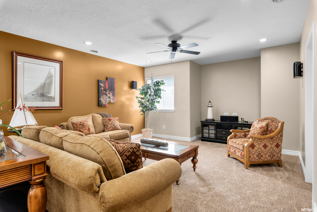 Living room featuring a textured ceiling, light carpet, and ceiling fan