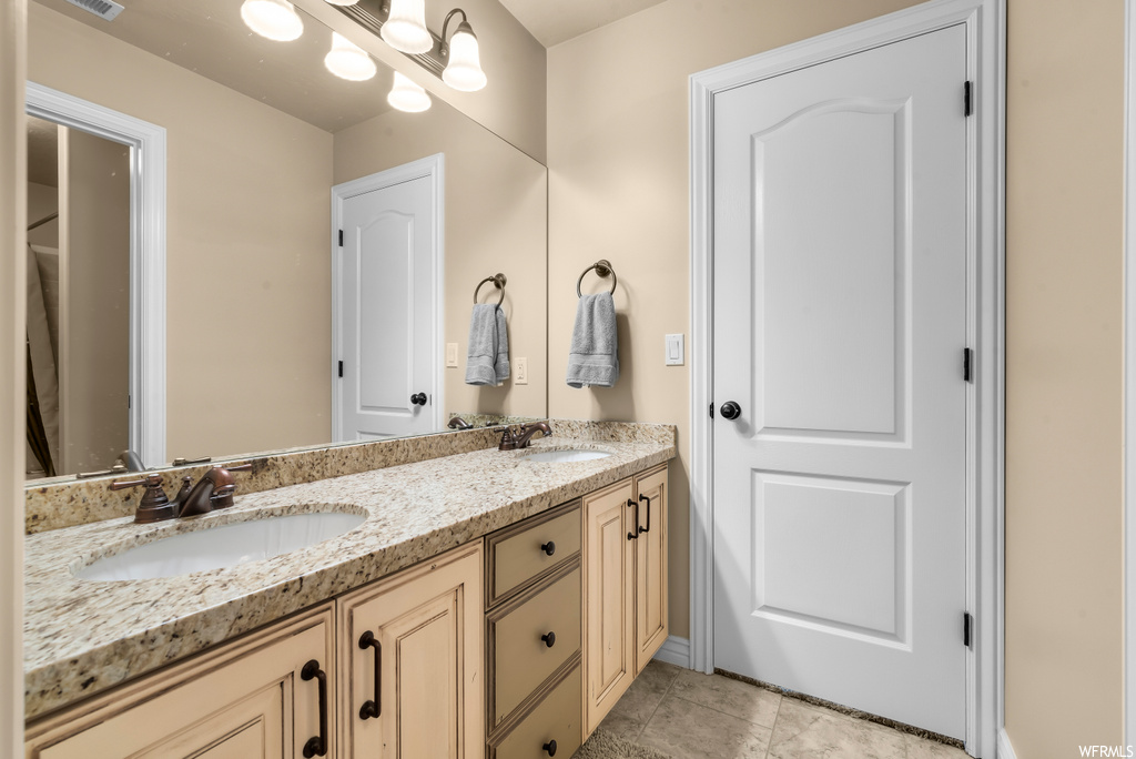 Bathroom featuring dual large vanity, mirror, and light tile floors