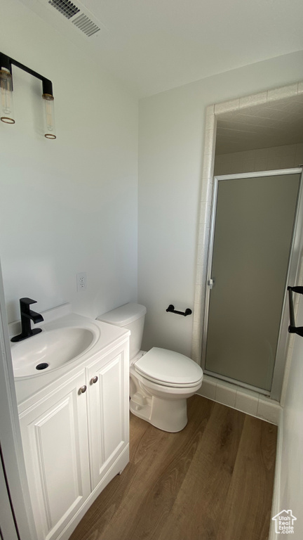 Bathroom featuring vanity, toilet, walk in shower, and hardwood / wood-style flooring