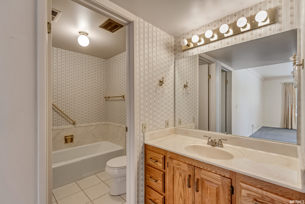 Bathroom with crown molding, vanity, mirror, and light tile floors