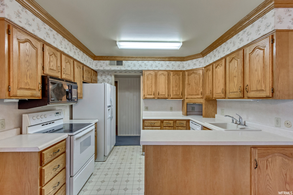 Kitchen featuring brown cabinets, light countertops, white appliances, ornamental molding, and light tile floors