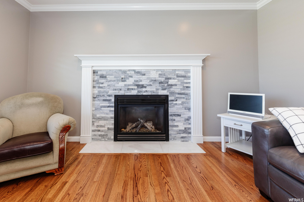 Living room featuring a fireplace, light hardwood floors, and crown molding