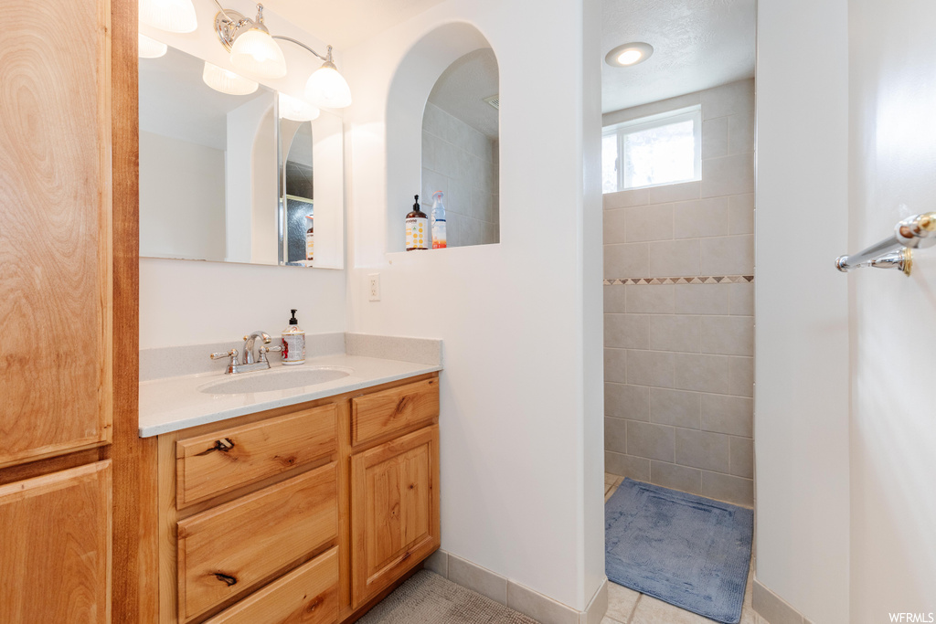 Bathroom featuring light tile floors, mirror, and vanity