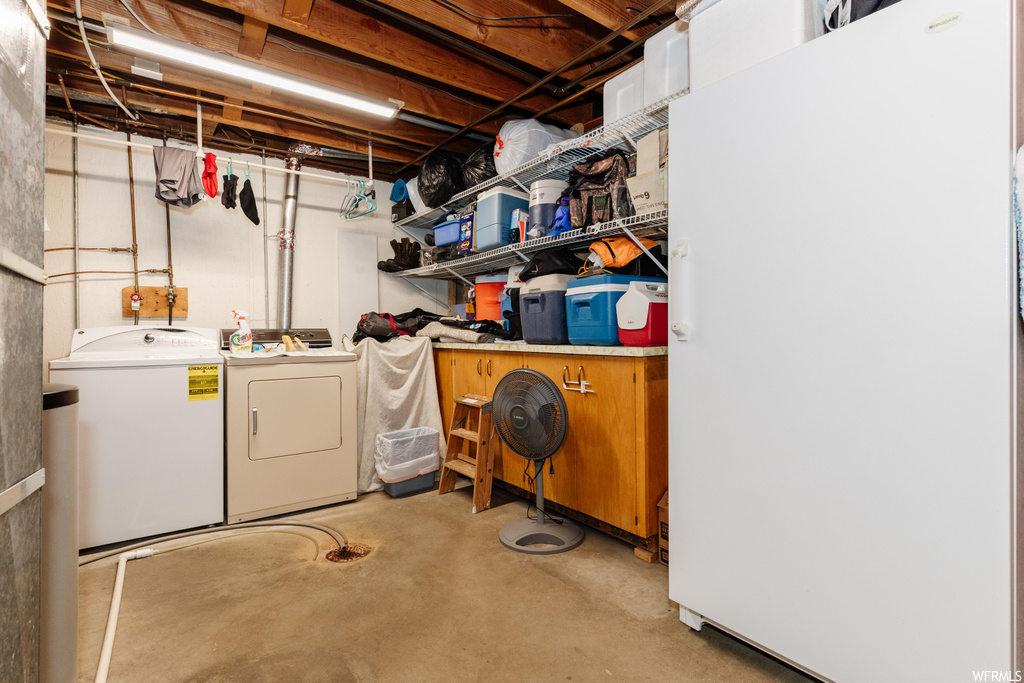 Basement featuring white fridge and washer and clothes dryer
