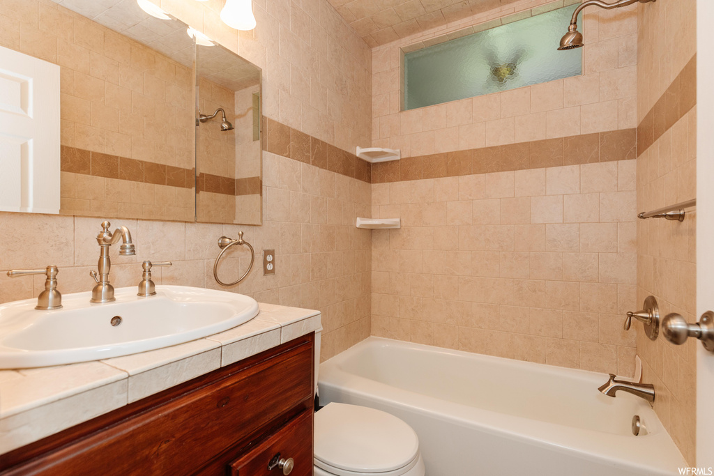 Full bathroom featuring tiled shower / bath combo, vanity, mirror, tile walls, and backsplash