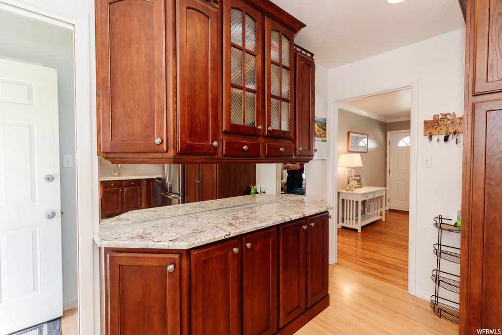 Kitchen featuring light stone counters, ornamental molding, and light hardwood floors