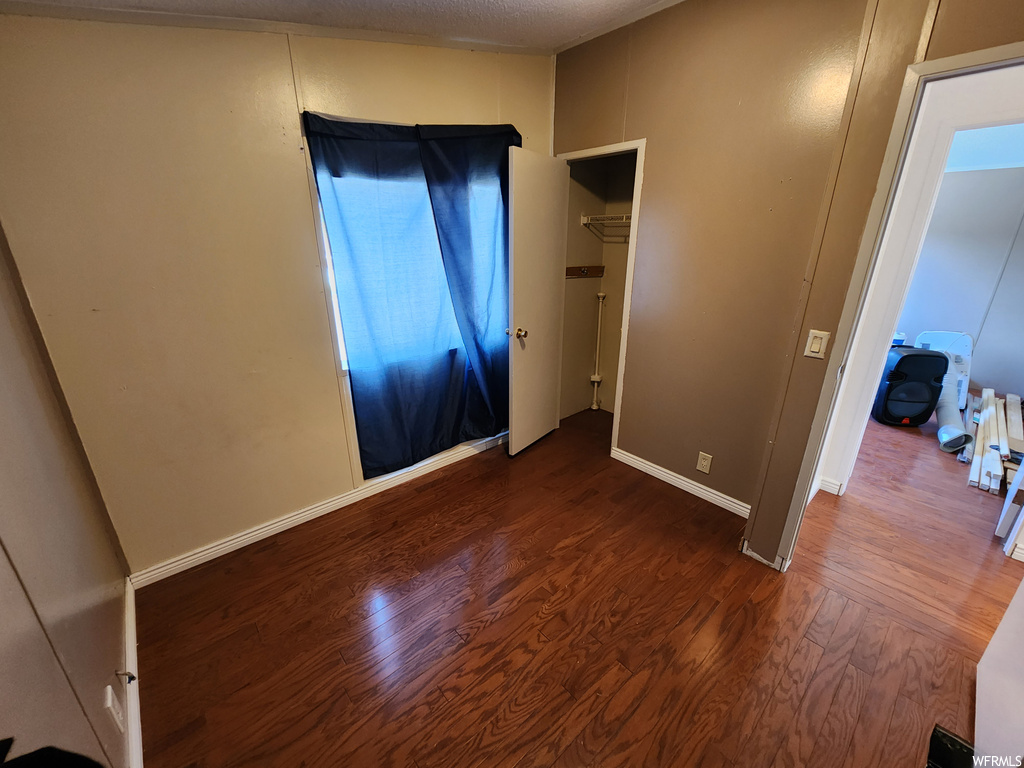 Unfurnished bedroom with dark hardwood floors and a textured ceiling