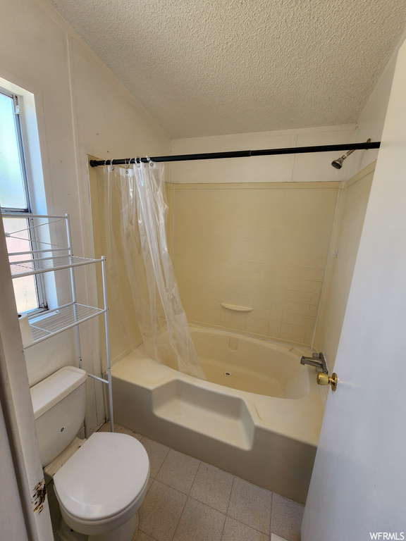 Bathroom featuring tile floors, a textured ceiling, shower / tub combo, toilet, and plenty of natural light