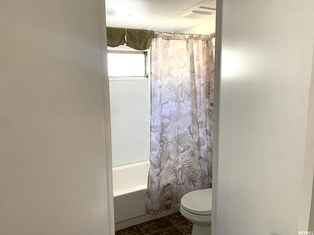 Bathroom with tile floors, toilet, and shower / bath combo