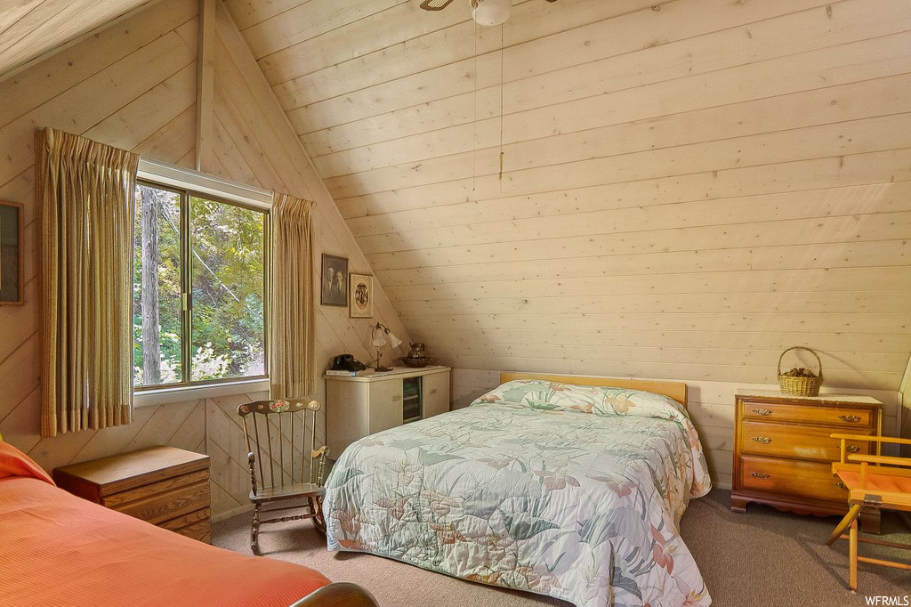 Bedroom featuring wooden walls, carpet, and lofted ceiling