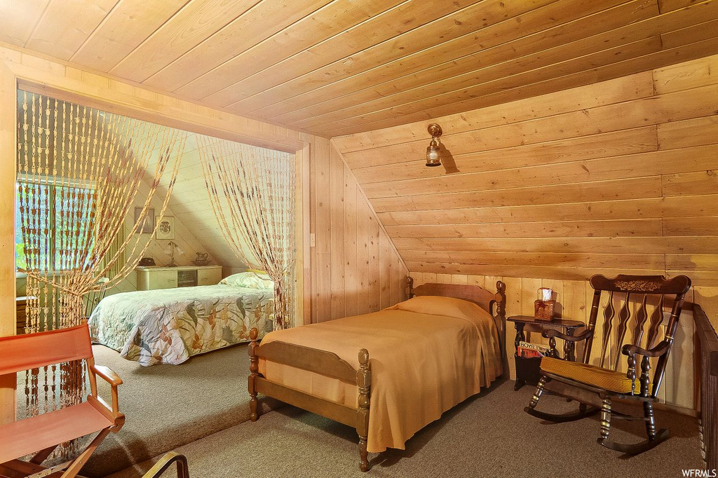 Bedroom with carpet flooring, wooden walls, wood ceiling, and lofted ceiling