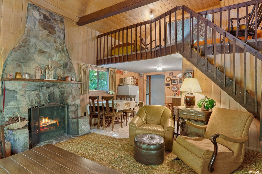 Living room featuring wooden walls, wooden ceiling, beam ceiling, and a fireplace