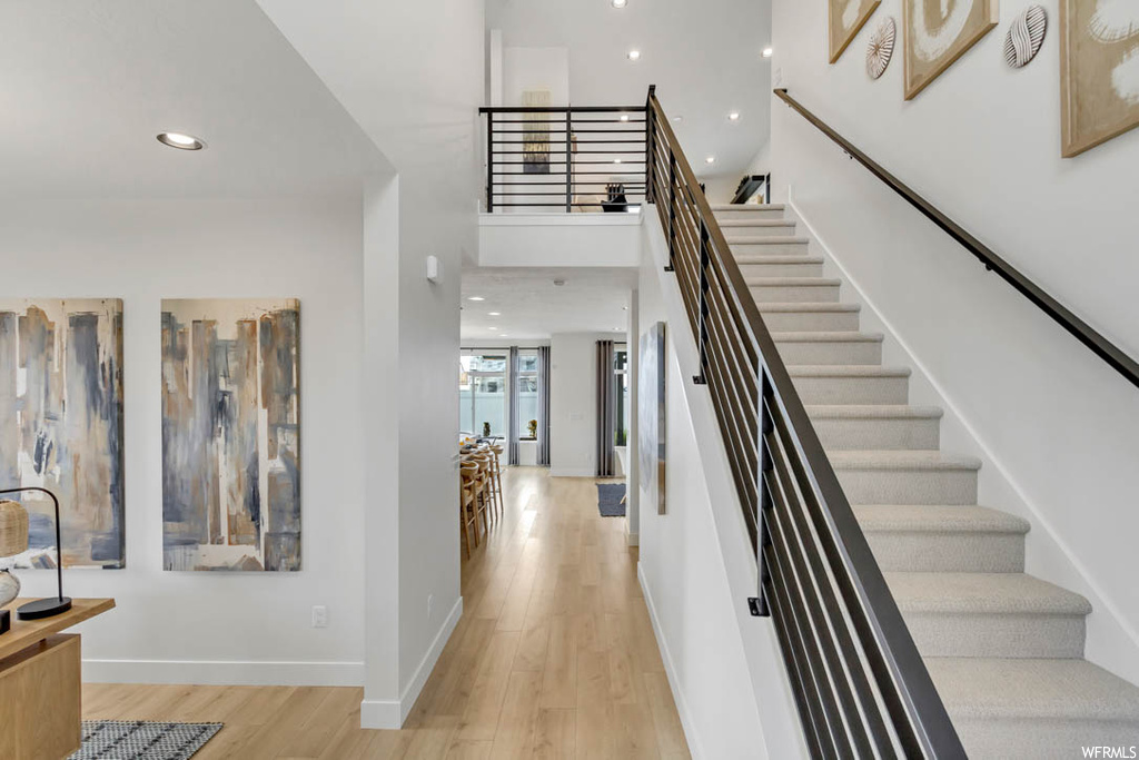 Stairs featuring a towering ceiling and light hardwood flooring