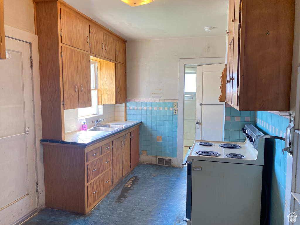 Kitchen with a healthy amount of sunlight, sink, tasteful backsplash, and white electric range